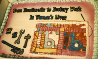 Color close-up of a large sheet cake. Large words: “From Handicrafts to Factory Work in Women’s Lives” with images of tools and a quilt. See Resources for full description.