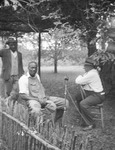 Black-and-white photograph of John A. Lomax and two African American men, with a microphone set up between them