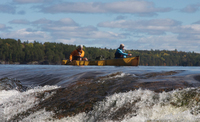 A color photograph of two canoeists paddling Wenonah Kevlar canoes.