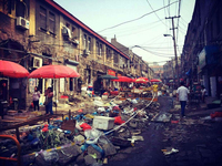 Photo showing a street covered in debris, with market vendors selling their goods under parasols.