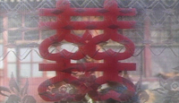 A red papercut of the double happiness character, which hangs on a window.