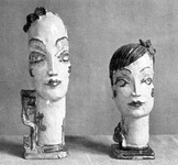 Black-­and-­white photograph of two ceramic earthenware heads, fashionably dressed in a 1920s style.
