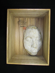 Photograph of a white plaster mask in a wooden box, with black calligraphy and red seal.