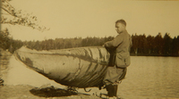 A photograph of Jule Marshall carrying his canoe, Babishe.