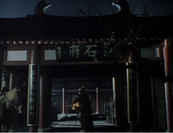 A figure stands under an archway at night, framed by calligraphy.