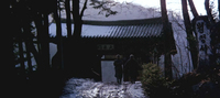 A sign over an entranceway has black calligraphy printed on it.