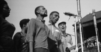 The Freedom Singers (from left): Rutha Mae Harris, Bernice Johnson (partially hidden), Cordell Reagon and Charles Neblett are joined by Pete Seeger (far right) in performance at the 1963 Newport Jazz Festival. Photograph copyright Daniel Gomez-Ibanez, 1963.