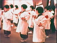 Figure 8.2. Seven bobbed haired girls dance, holding Japanese flags, with white sashes printed “Beloved Horse Girls Group of Gion” worn diagonally across the shoulders.