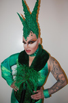 Three-quarters image of Nina Flowers with foam headpiece, shiny clothing, tattoos, and feathers.