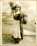 Black-and-white photograph of actress Sonia Alomis carrying a bale of hay.