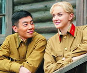 A young Pang Tiande and Natasha happily chatting in front of a hut. They both wear Soviet military uniforms. Natasha smiles sweetly, while Pang gazes at her affectionately.