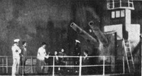 Production photograph depicting gunboat set piece and actors aboard deck of ship.