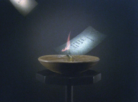 A sheet of paper with writing on it is dropped onto a small lantern