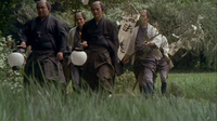 Men walk through a field holding lanterns and a banner with black calligraphy written on it.