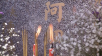 Incense burns in front of a tombstone's calligraphy.