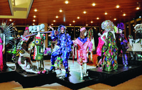 The costume designer in drag in front of mannequins wearing his designs for A 24-­Decade History of Popular Music in San Francisco, California.