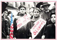 Two girls march with others in parade. Both hold flags; one is the American flag. They wear ribbons across their chest. One reads “Abolish Child Slavery.” The other is in Yiddish.