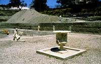 Photograph of a crater and Hermaphrodite group in foreground and statues of headless Nike and ephebe and herm of Hercules arranged along east side of the pool at Villa A Oplontis.