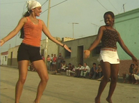 An still image from film showing Cynthia Paniagua being instructed in Afro-­Peruvian dance while visiting Ballumbrosio family studio as neighbors watch.