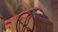 A cartoon of a figure sleeping on top of a wooden box and wheel, which has faded calligraphy on it.