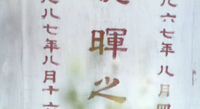 A close-up shows red calligraphy on a gravestone.