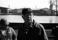 A portrait of a Lake Erie Fisherman wearing glasses and a hat, looking slightly left to the camera.