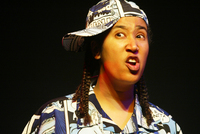 Figure 15. The photo is a close up of Aya de León as a wigga, a white teenage wannabe hip hop thug, in Thieves in the Temple (2002). De León has a smirk on her face and wears a blue hat and shirt.