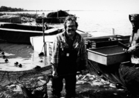 A photograph of Tim Lloyd, author, holding a net on the dock with seine behind him.