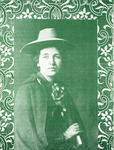 Half-length photo of younger Flynn with a broad-brimmed hat, a coat, a scarf, and gloves. She looks pensive and holds a book. Dark green with floral pattern border.