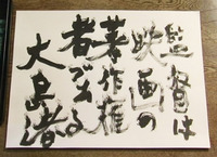 A film still of black calligraphic text written on white paper.