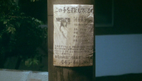 Close-up image of a pole with a poster tacked to it that has calligraphy and a photograph of a person.