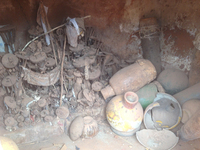 To the left, a dense collection of aging metal fixtures honoring the ancestors of the family. To the right, drums made of wood, skin, and gourds where they are stored in the shrine. A broken calabash drum sits in front.