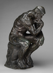 Photo of a sculpture titled The Thinker by Rodin. This is a bronze sculpture of a naked man in a sitting position with his left arm draped over his knee and his right elbow on his knee. His hand is bent under his chin as if he is thinking