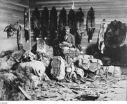 A black-and-white photograph of a figure sitting in a room full of furs.
