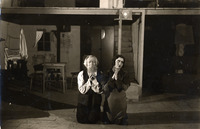 Black-and-white photograph of two actors kneeling on a stage