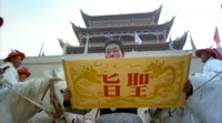 Shot from below, a man reads from a scroll that has a decree from the emperor. Two large characters are on the back.