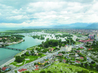 Panoramic view of Buna River and Shkodër Lake from the Shkodër Castle, with the Bjeshkët e Namuna Mountains in the background.