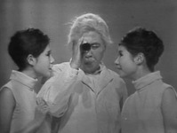 Black and white still of two women (singing duo, the Peanuts) on either side of man (Hana Hajime). Women turn in to face man who holds telescope up to eye and peers in direction of viewer.