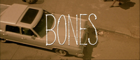 An English title is superimposed over a car in a sepia screenscape. The unique handwritten design for _Bones_ is by Pablo Ferro, who first used this style for _Dr. Strangelove_.
