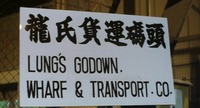 A close-up of black calligraphy on matte white in partial English, posted to a fence.