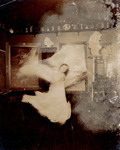 A black and white photograph of Loïe Fuller as a blurred figure in an atelier space (1899-­1900).