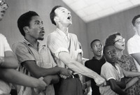 Free Southern Theater guitarist Roger Johnson crosses his arms and joins hands with legendary folk singer and activist Pete Seeger to sing “We Shall Overcome” at Mt. Zion Baptist Church, August 4, 1964, during the Freedom Summer in Hattiesburg, Mississippi.