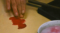 person using finger tips to apply red ink on drawing