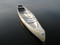 A color photograph of an aluminum Grumman canoe on the water.