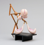 The color photograph is a three-quarter view of The Machine-Gunneress in a State of Grace built by Hans Bellmer in 1936. The doll sculpture consists of a conic head, with a suggestive cleft on the top and a mouth at the bottom, two small breasts, and two large spoon-shaped limbs; a small wooden sphere around which the whole machine is articulated; and broom handles with moveable joints.