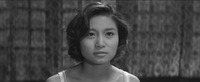 A widescreen close-­up on desperate pregnant teen Etsuko, with bland curtains making up the entire background. Her expression seems in equal parts needy and vacant.
