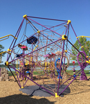 A photograph of an empty, purple, polyhedrol play structure in a playground park.