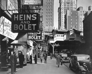 A bustling street, near an elevated train station, with stores selling radios, appliances, and electronic parts.