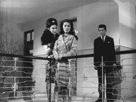 A black-­and-­white shot from The Best Secret Agent showing two women and a man standing on the balcony of a living room.
